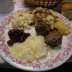 Clockwise from the top: mashed potatoes and gravy, rutabaga, meatballs, lutefisk with melted butter, cranberry sauce and coleslaw